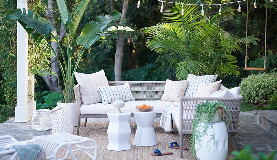 Top 10 Spring Must Haves To Prep Your Outdoor Space Com Lush Green Backyard With Cozy Outdoor Furniture White Pillows And Accent Tables